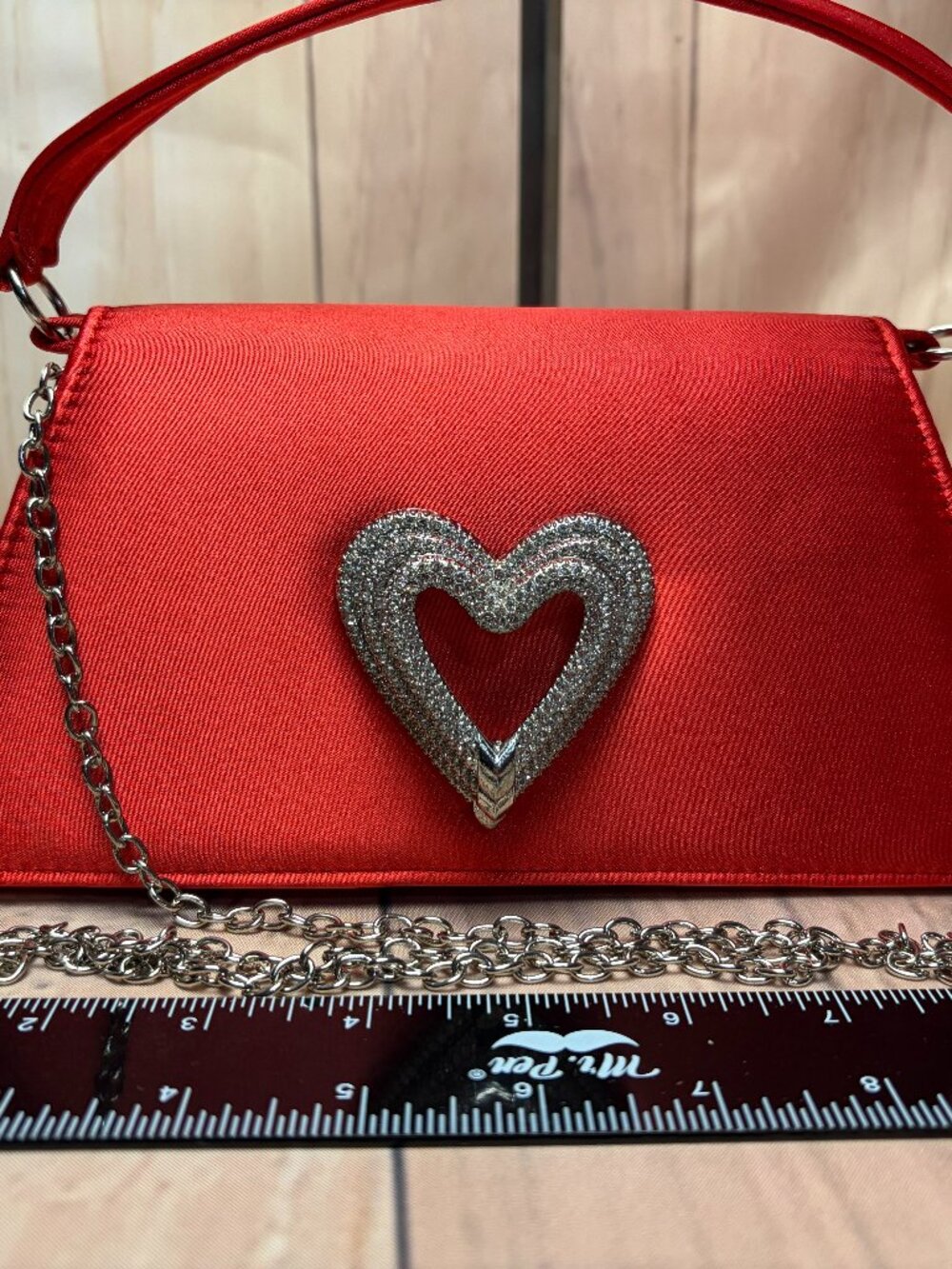 Red satin trapezoid handbag featuring a sparkling rhinestone heart accent